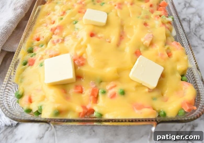 Chicken and rice casserole dish with creamy soup mixture poured over the top, before baking