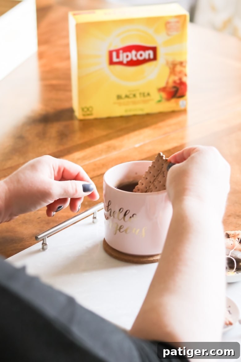 Craft Your Own Tea Lovers Basket 5 Enjoying a moment of tranquility, dunking a delicate tea biscuit into a warm mug of Lipton Black Tea, with the distinctive Lipton tea box visible in the background.
