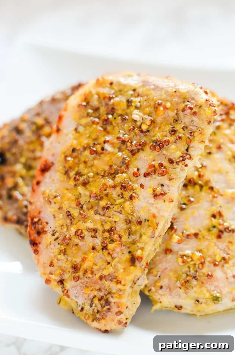 Juicy oven roasted pork chops with a delicious honey and grainy mustard sauce, served with roasted vegetables.