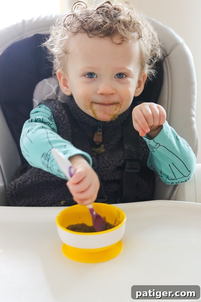 Toddler learning how to use a spoon, a messy but important developmental stage