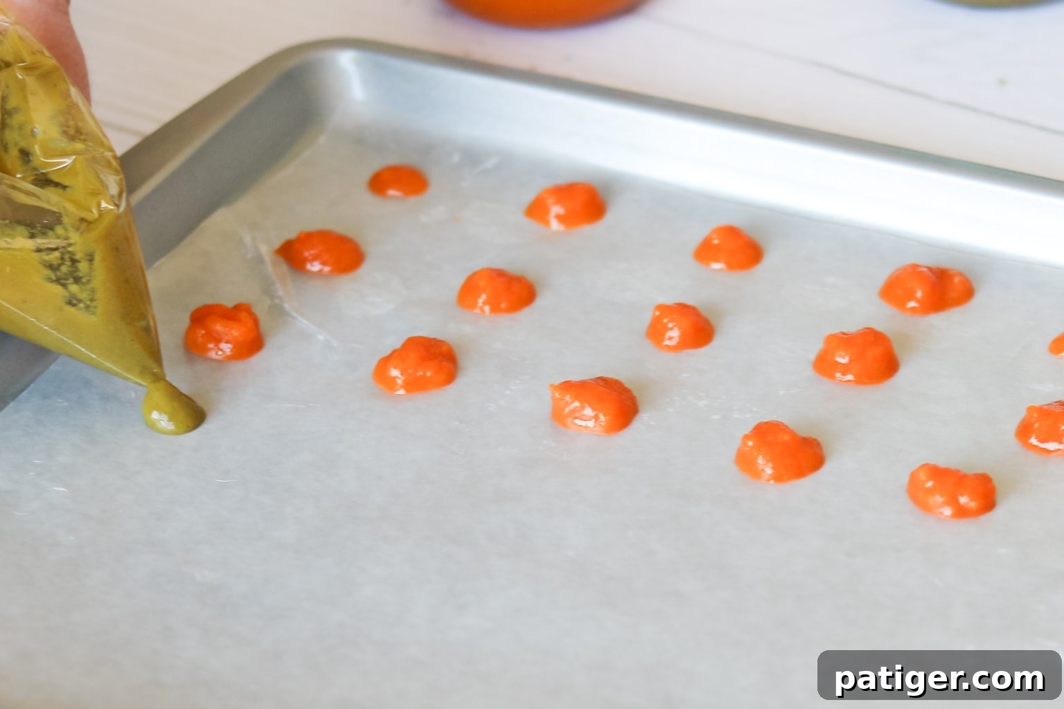 Piping small dots of baby food onto a lined baking sheet
