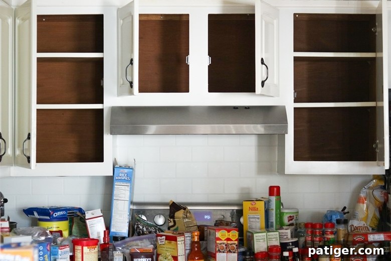 Empty cabinets with a lot of pantry items removed and placed on countertop underneath