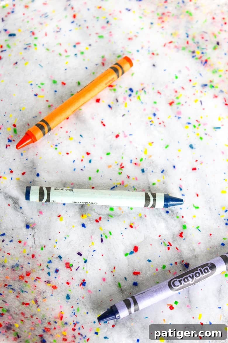 Colorburst Crayon Slime 3 Close-up of a child's hands stretching colorful crayon slime, highlighting the embedded crayon shavings. An easy and engaging DIY project that encourages recycling.