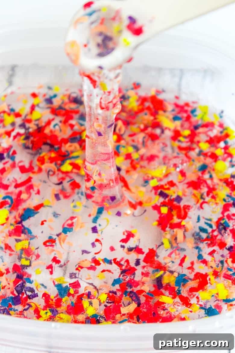 Colorburst Crayon Slime 6 A bowl containing slime ingredients being stirred with crayon shavings, illustrating the process of how to make crayon slime.