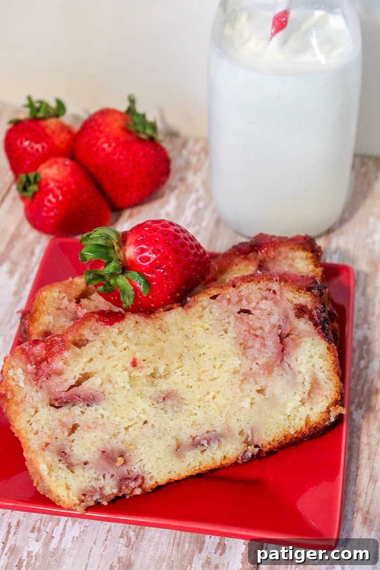 Two generous slices of strawberry yogurt pound cake on a vibrant red plate, garnished with fresh whole strawberries.