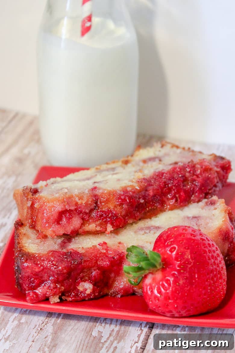 Two elegant slices of strawberry pound cake on a red plate, accompanied by a fresh strawberry and a glass of milk with a striped straw.