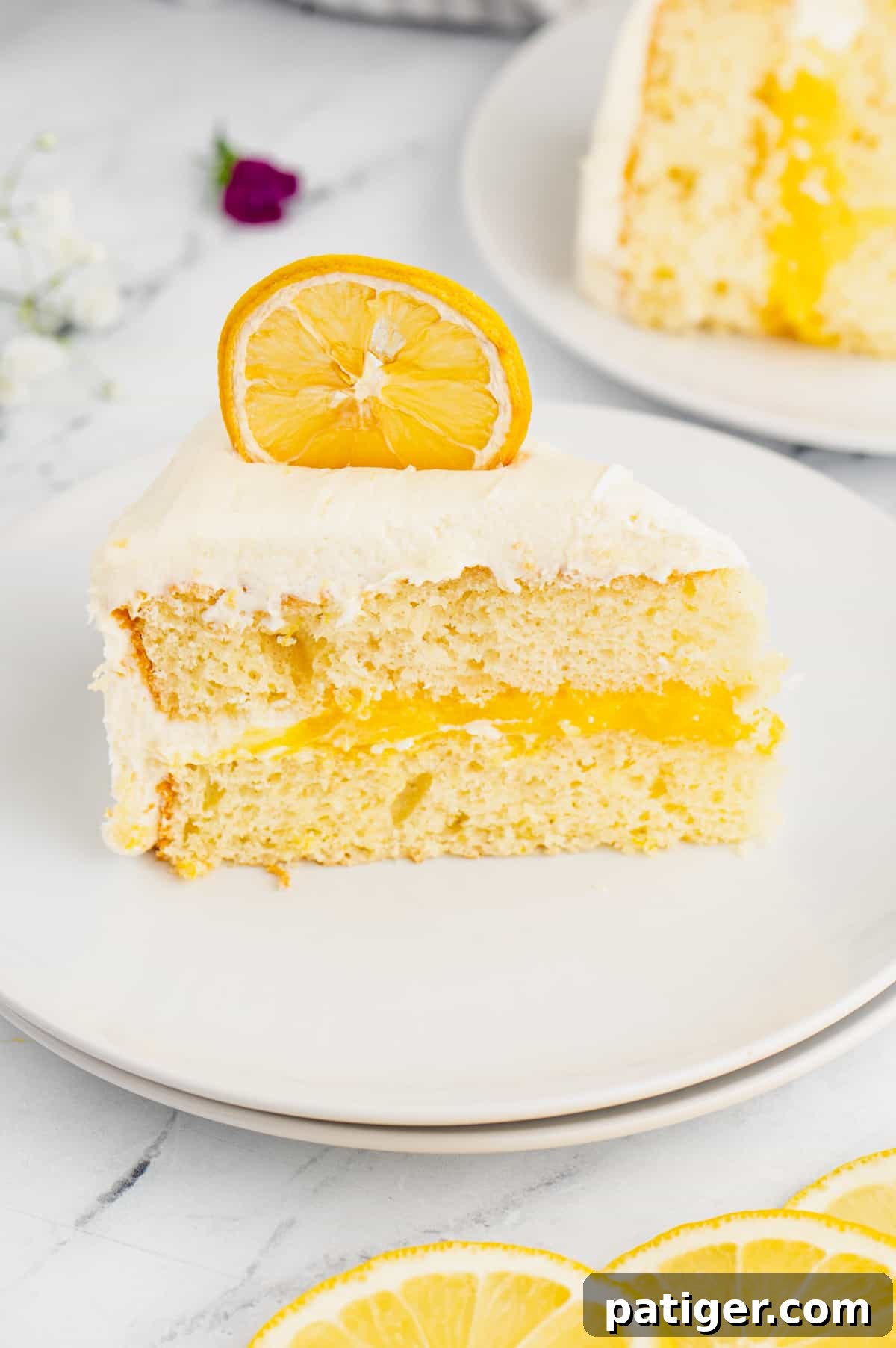 Slice of lemon layer cake with lemon curd filling and marshmallow frosting.