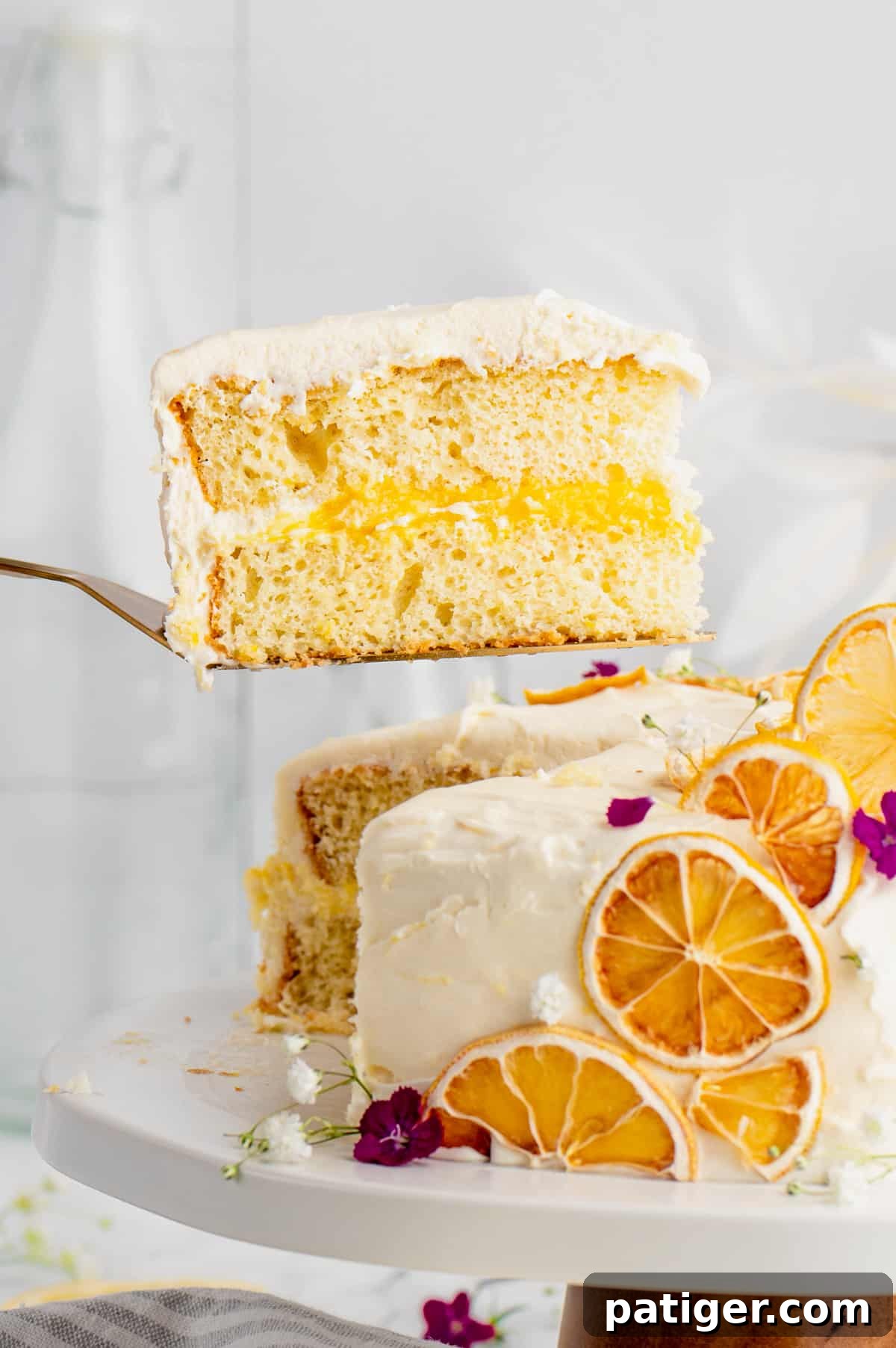 Slice of lemon curd cake being removed from cake with a cake server.