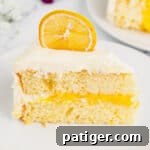 Slice of lemon layer cake with lemon curd filling and marshmallow frosting.
