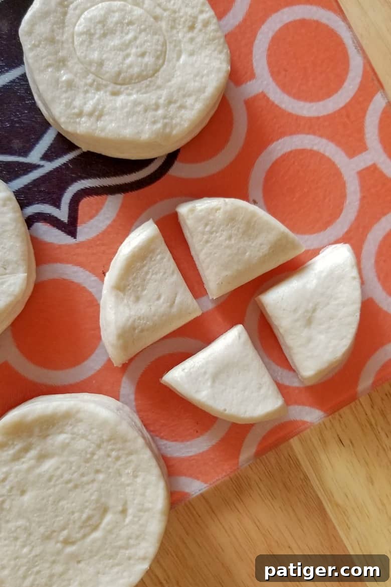 Close-up view of canned biscuits being cut into quarters on a cutting board, ready for the Instant Pot.
