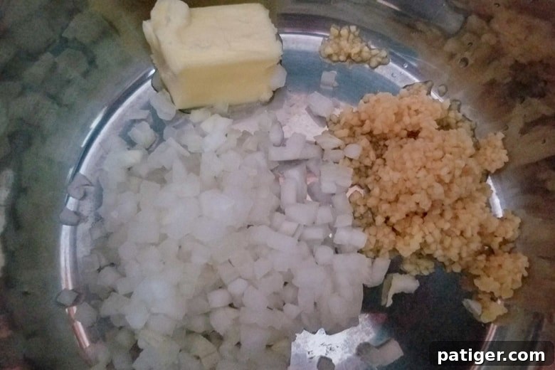 Diced onion, melted butter, and minced garlic simmering in the Instant Pot on the 'Saute' setting, creating a fragrant base for the chicken and dumplings.