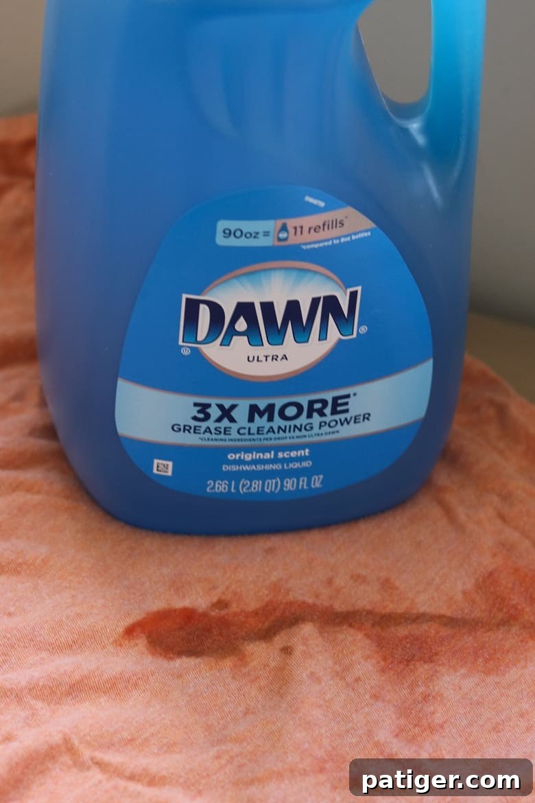 Container of blue Dawn dish soap on top of a stained orange shirt