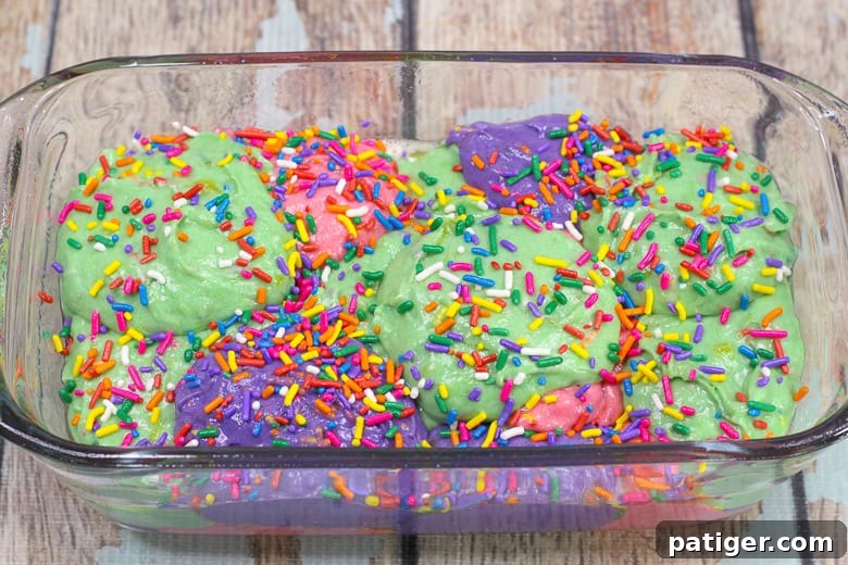Magical Mornings Start with Unicorn Bread 4 Pink, purple, and green batter in a 9 x 9 loaf pan, with sprinkles on top, ready for baking.