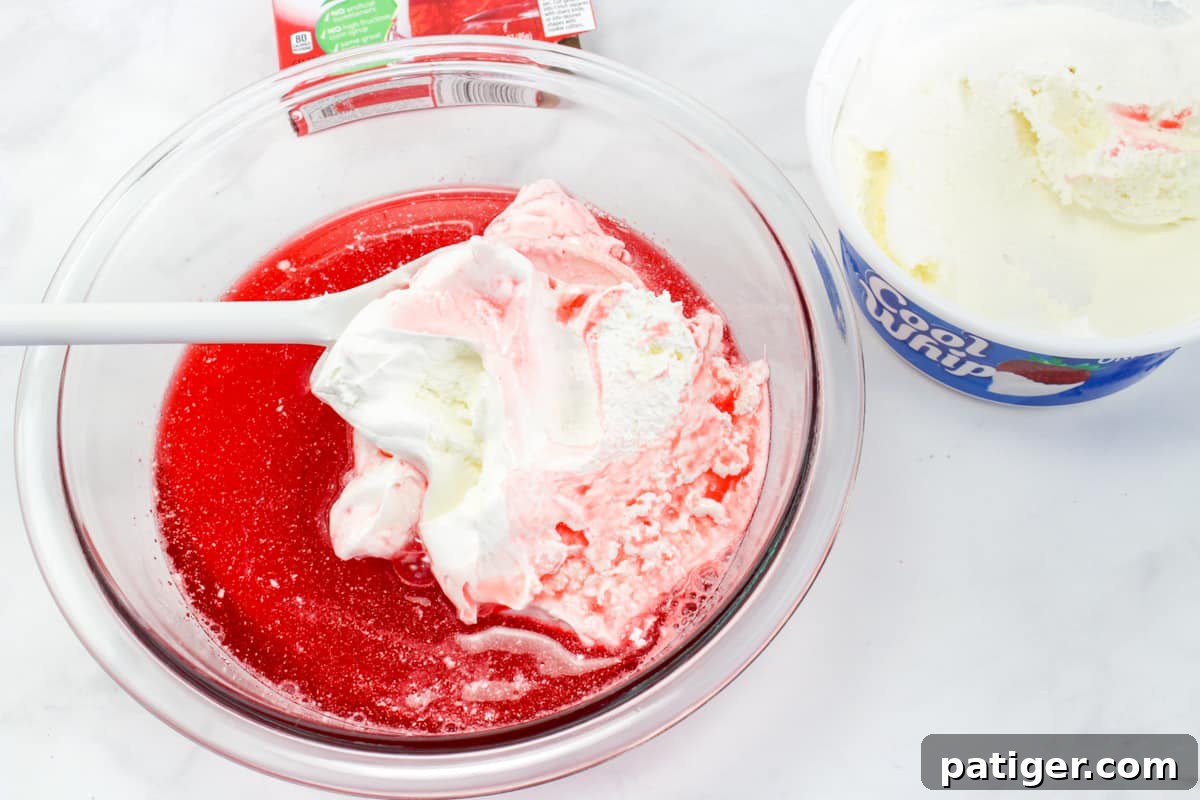 Cool Whip being mixed into jello mixture.