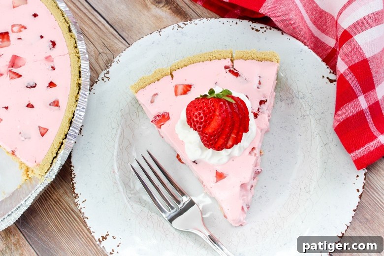 Slice of Strawberry Jello Pie on white plate, garnished with whipped cream and strawberries