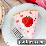 Slice of Strawberry Jello Pie on white plate, garnished with whipped cream and strawberries