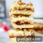Peanut butter and jelly cookie bars with peanut butter chips and a layer of jam spread between two butter cookie layers.