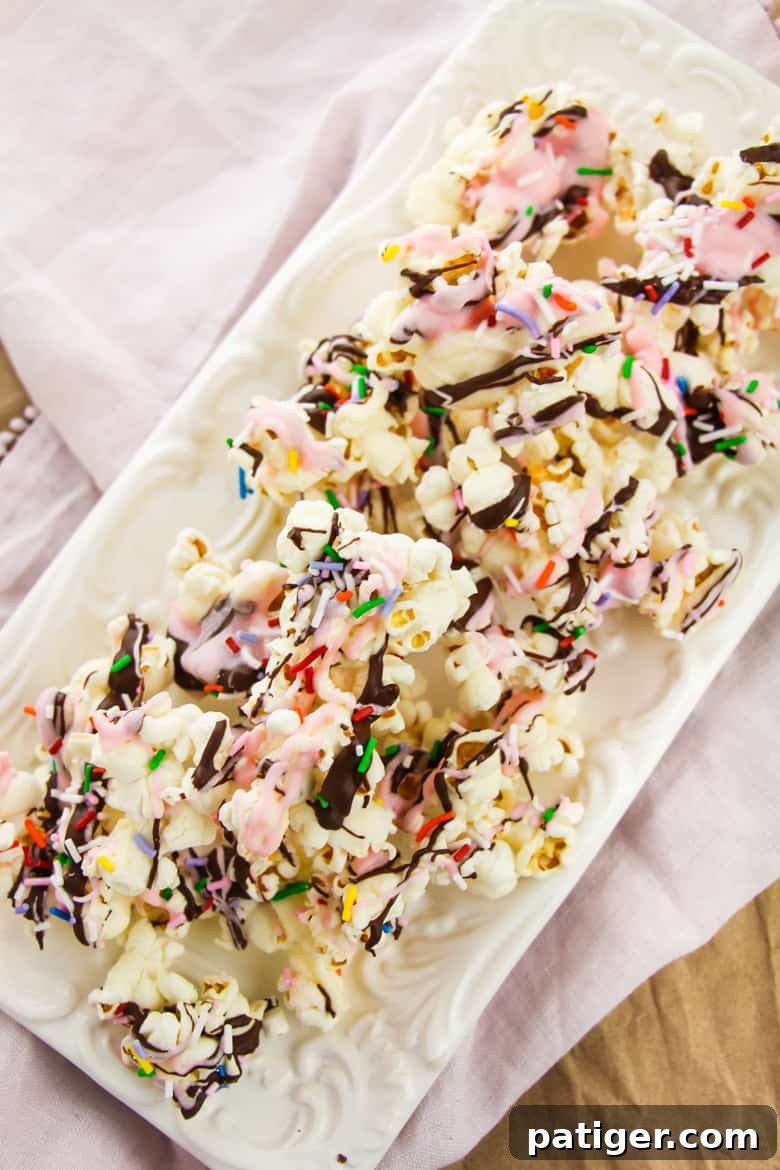 Sundae chocolate covered popcorn with sprinkles, featuring colorful drizzles and toppings