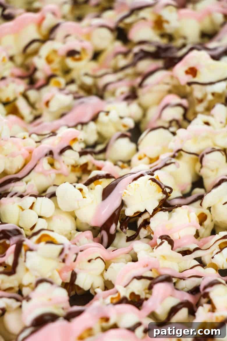 Popcorn being drizzled with melted chocolate on a baking sheet