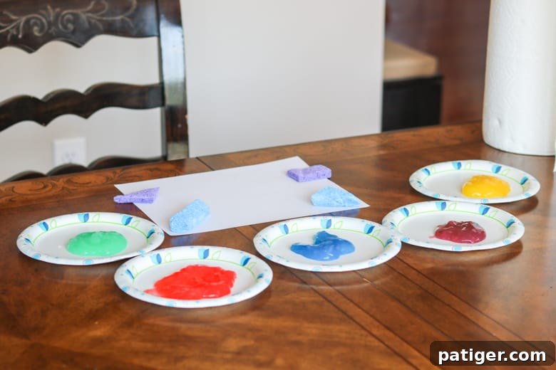 A setup with homemade toddler paints in various colors, paper, and sponges, all ready for an engaging art activity.