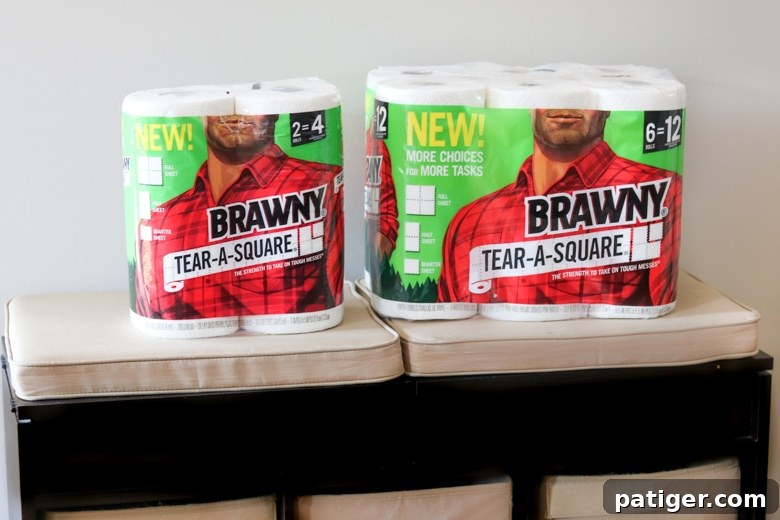 A roll of Brawny® Tear-A-Square® paper towels sitting neatly on a wooden bench, highlighting its readiness for any mess.