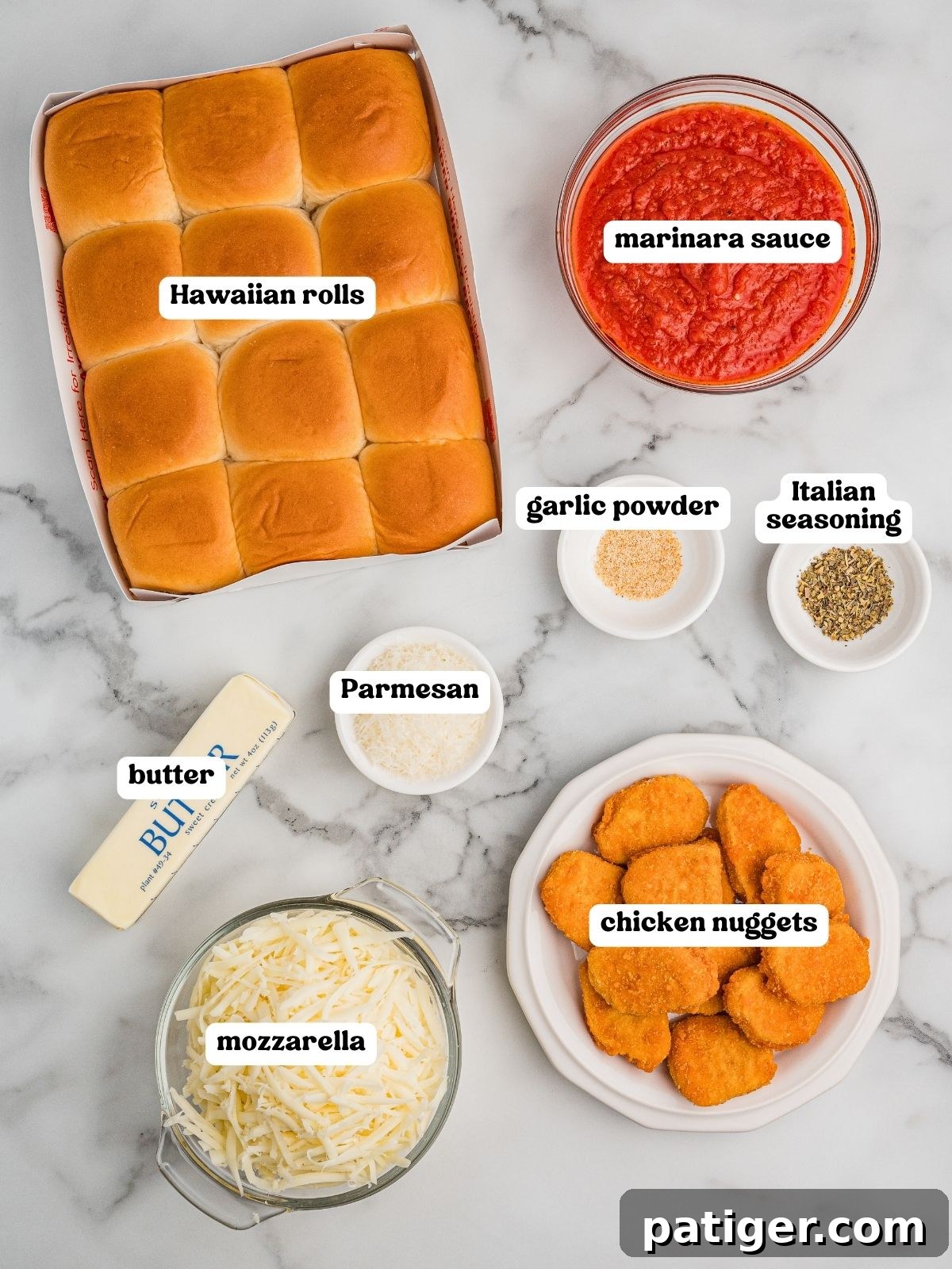Labeled ingredients for chicken parm sliders on a marble surface: a package of Hawaiian rolls, a bowl of marinara sauce, a stick of butter, shredded mozzarella, grated Parmesan, cooked chicken nuggets, garlic powder, and Italian seasoning.