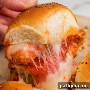A chicken parm slider with nuggets and melty cheese being pulled from the pan.