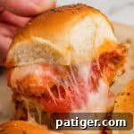 A chicken parm slider with nuggets and melty cheese being pulled from the pan.