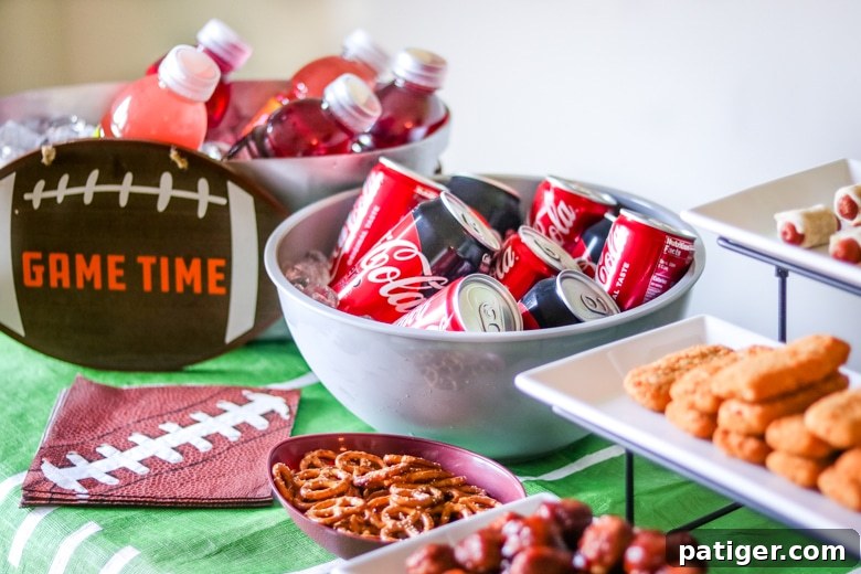 The Ultimate Game Day Playbook 40 Easy Recipes 3 A festive game day food table overflowing with an assortment of snacks, savory finger foods, refreshing sodas, and flavored water bottles chilled on ice, ready for a party.