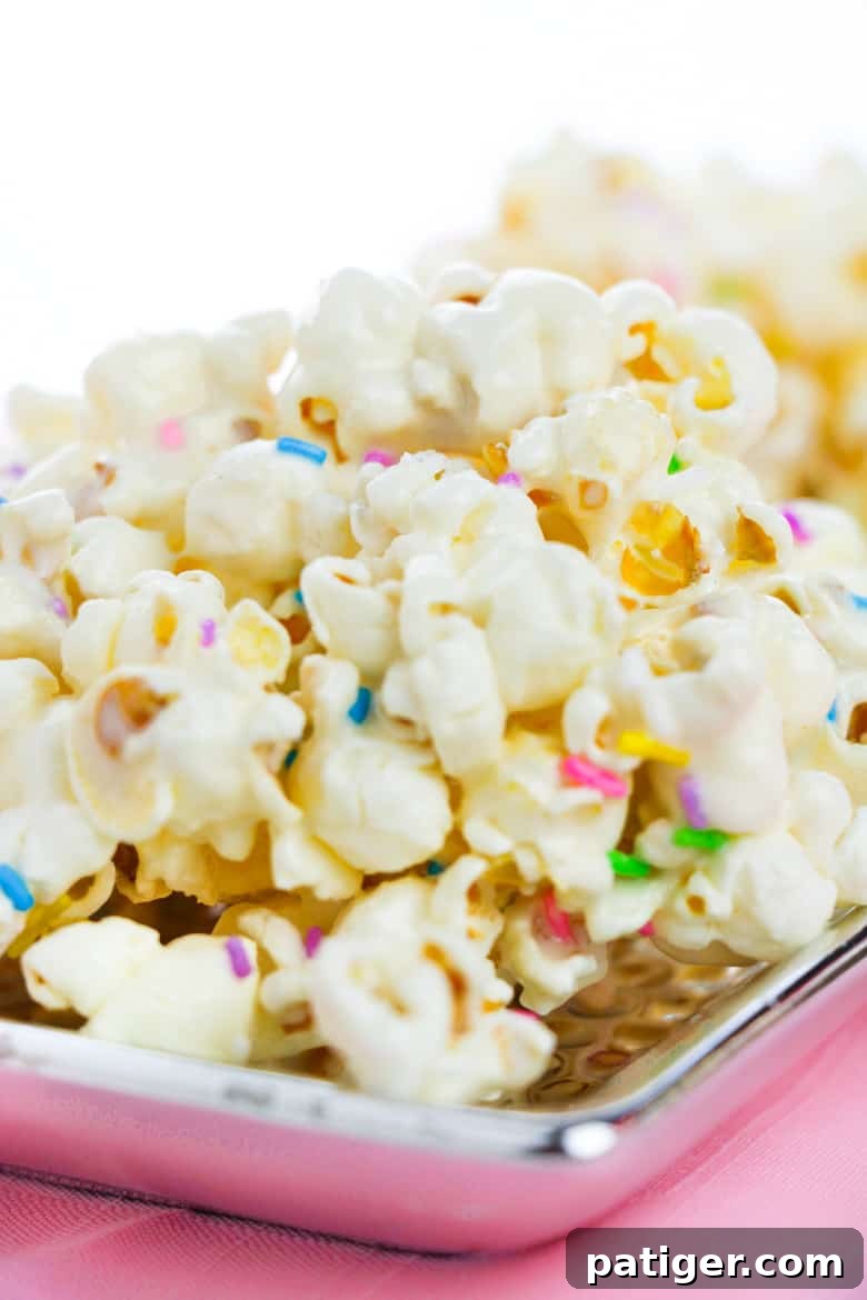 A silver platter showcasing cake batter popcorn generously topped with an array of rainbow sprinkles, highlighting its vibrant and inviting appearance.