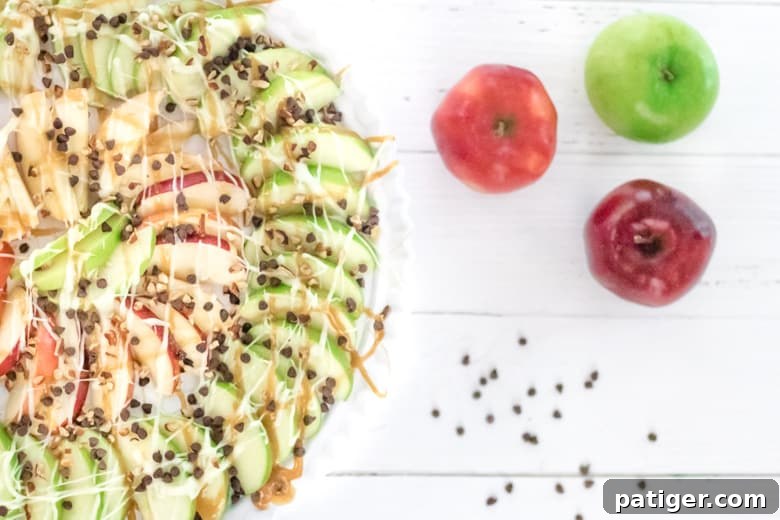 Caramel Apple Nachos with red and green apple slices drizzled with caramel, melted chocolate, mini chocolate chips, and chopped pecans. A perfect fall dessert or quick snack.
