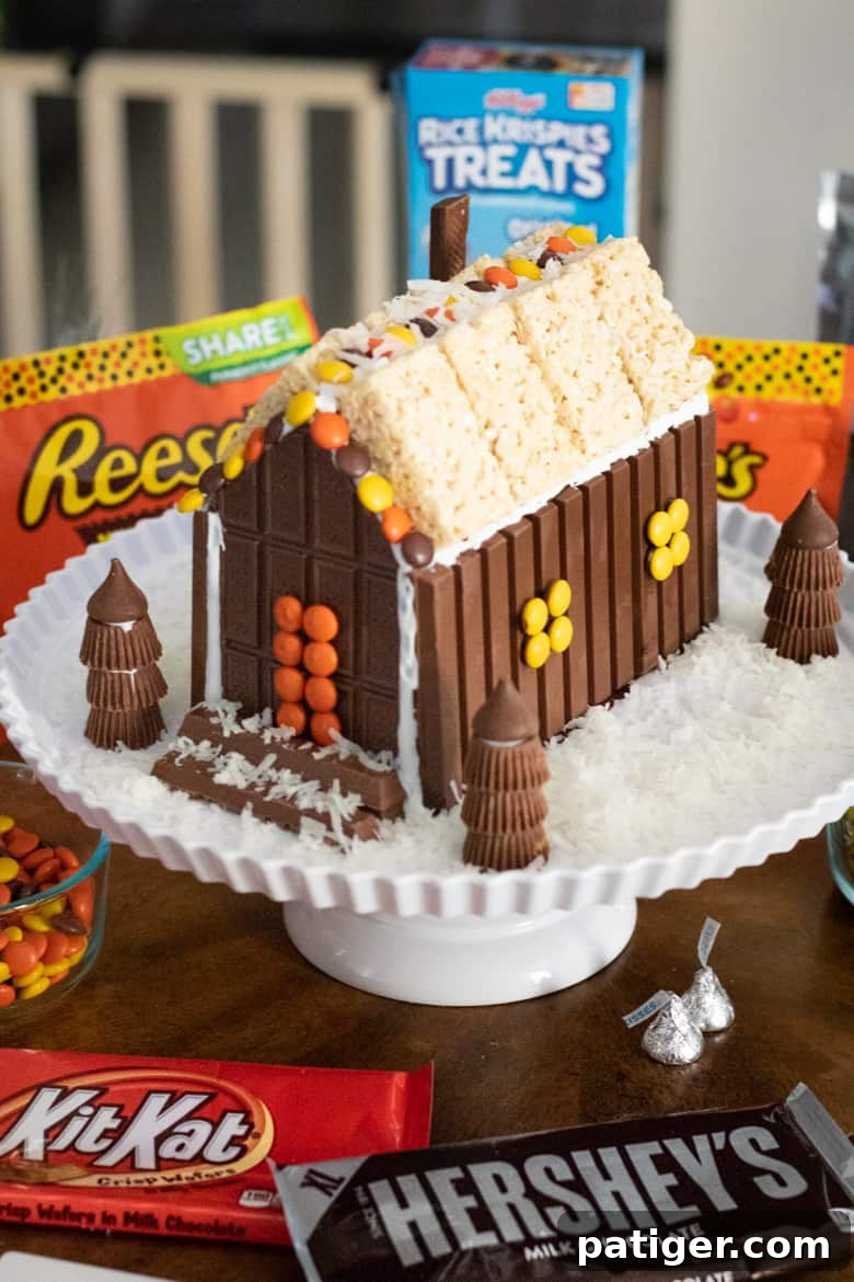 Festive Sweet Retreat 9 Christmas candy house made with chocolate bars, kit kats, reese's peanut butter cups, kisses, and rice krispie treats.