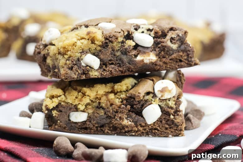 Cozy Hot Chocolate Brookies 3 Close-up of baked hot chocolate brookies, showcasing the gooey melted chocolate chips and perfectly toasted marshmallows on top of the golden-brown cookie layer and dark, fudgy brownie base.