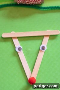 Googly eyes and a red pom pom nose glued onto the popsicle stick reindeer face, bringing it to life