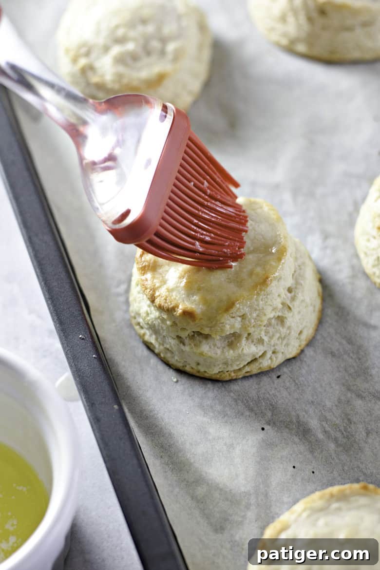 Fluffy Buttermilk Biscuits from Scratch 14 Freshly baked buttermilk biscuits being brushed with melted butter for extra flavor and shine.