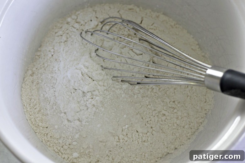 Fluffy Buttermilk Biscuits from Scratch 6 A large mixing bowl containing whisked dry ingredients for buttermilk biscuits: flour, baking powder, sugar, and salt.