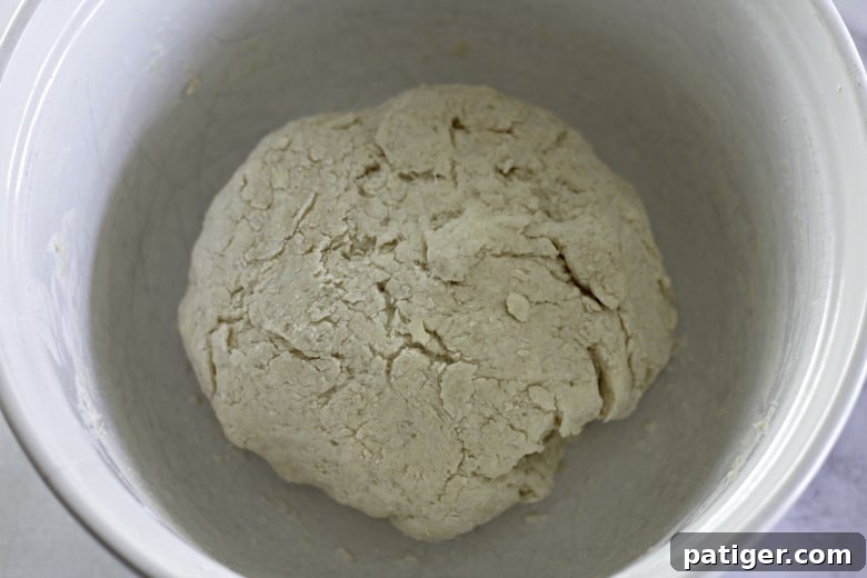 Fluffy Buttermilk Biscuits from Scratch 8 Buttermilk being poured into the dry ingredients and butter mixture, then gently stirred with a spatula to form biscuit dough.
