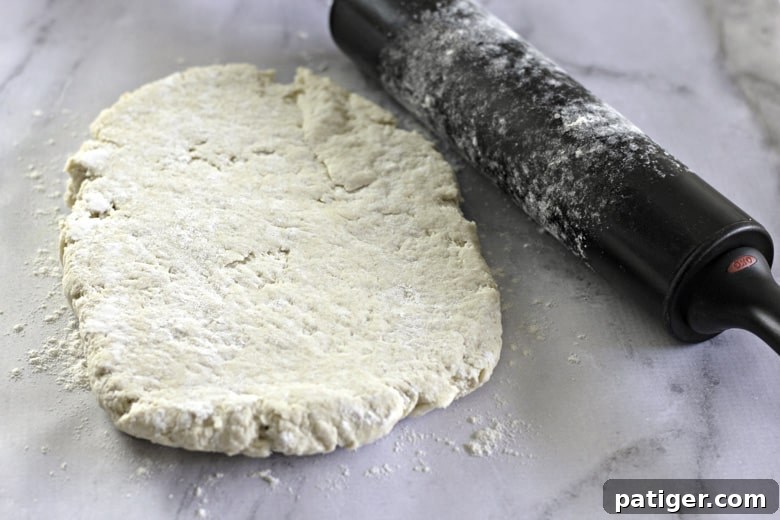 Fluffy Buttermilk Biscuits from Scratch 10 Biscuit dough rolled out on a floured surface after folding, ready for cutting into biscuits.