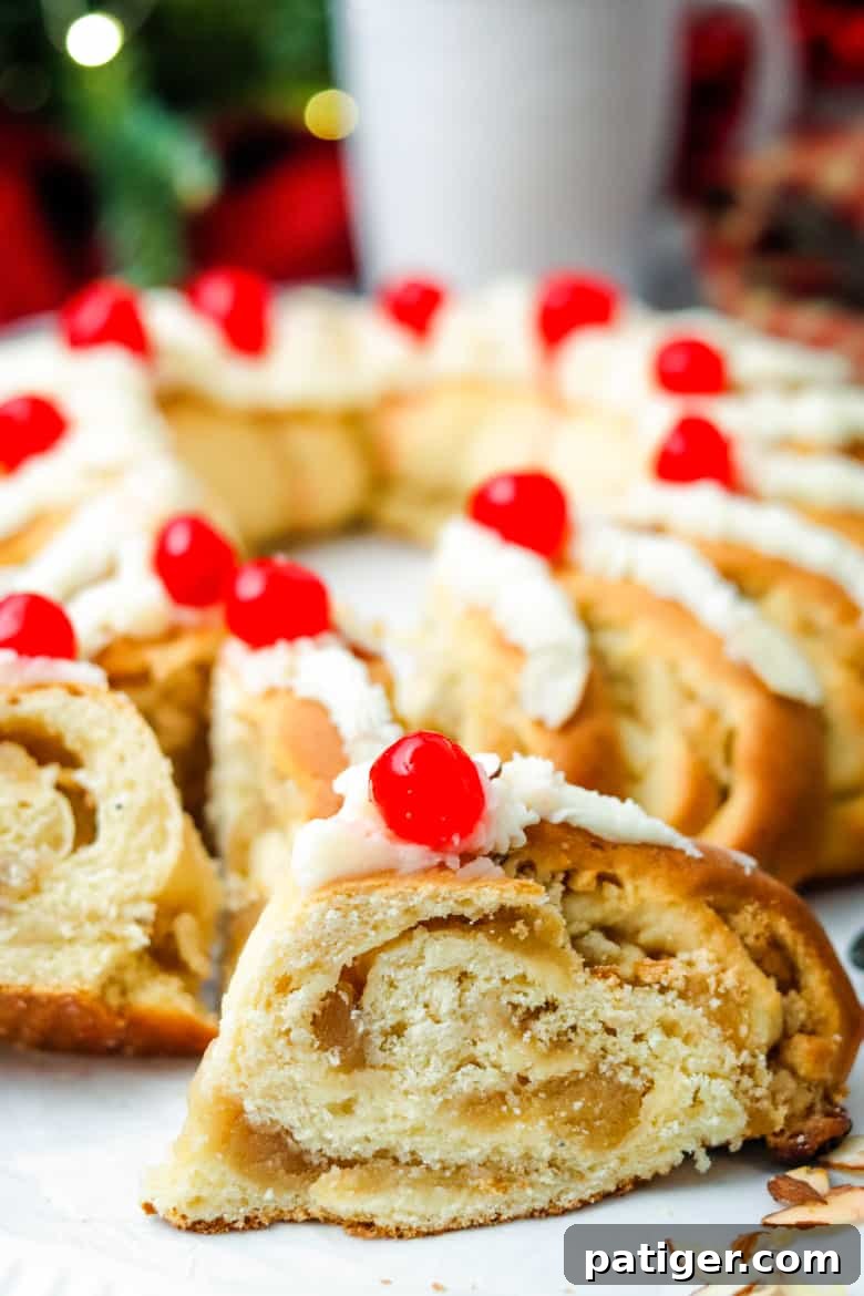 A slice of Swedish Tea Ring with the entire tea ring in the background, showcasing its festive shape and delicious filling.