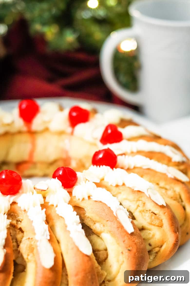A stunning Swedish Tea Ring adorned with creamy buttercream and bright red cherries, ready to be enjoyed.