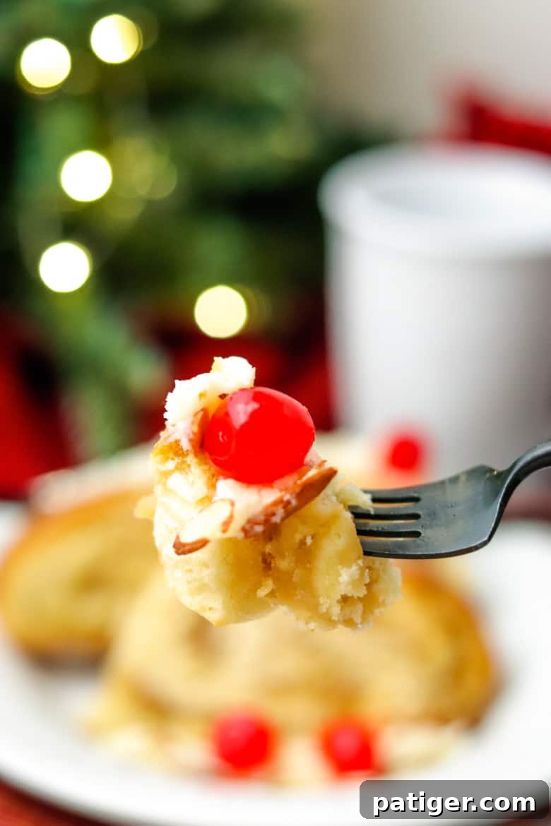 A single, delectable bite of Swedish Tea Ring on a fork, with the full pastry and a coffee mug blurred in the background, highlighting its inviting texture.