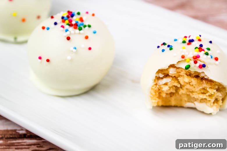 Close-up of freshly made sugar cookie truffles on a white plate, showcasing their delightful coating