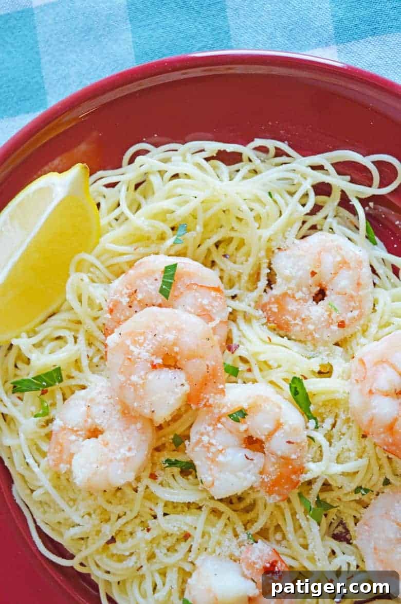 Lush shrimp scampi served over delicate angel hair pasta, garnished with a vibrant lemon wedge and fresh parsley.