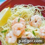 shrimp scampi over angel hair pasta served with a lemon wedge and topped with parsley