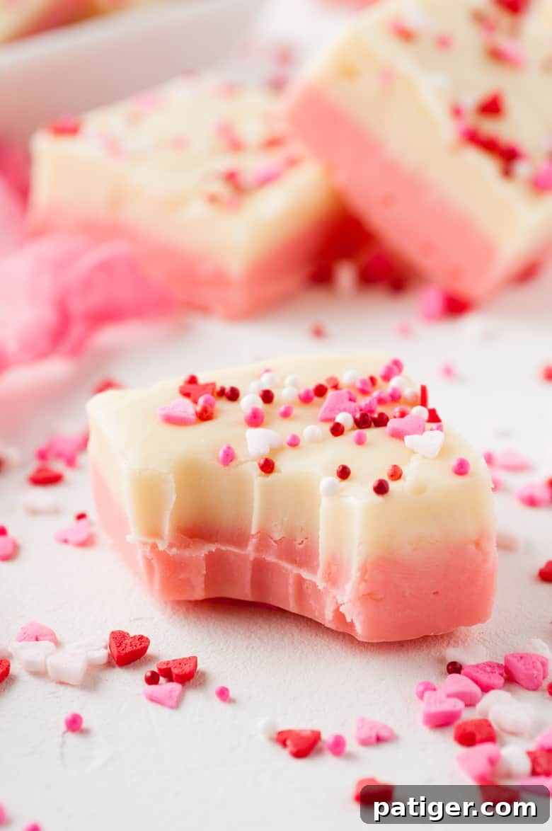 Velvet Valentine Fudge 2 Square of creamy white chocolate Valentines fudge with a bite mark and heart sprinkles.