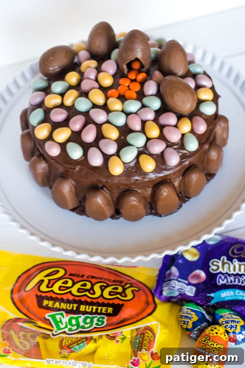 A beautifully decorated chocolate layer cake topped with an assortment of Easter candies, including Cadbury Creme Eggs, REESE’S Milk Chocolate Eggs, and sparkling Cadbury Shimmer Mini Eggs. The cake is the perfect centerpiece for Easter celebrations.