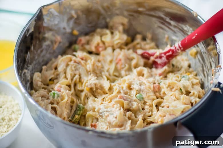 Mixing Chicken Casserole Ingredients in a large bowl with a red spoon, ready for baking.