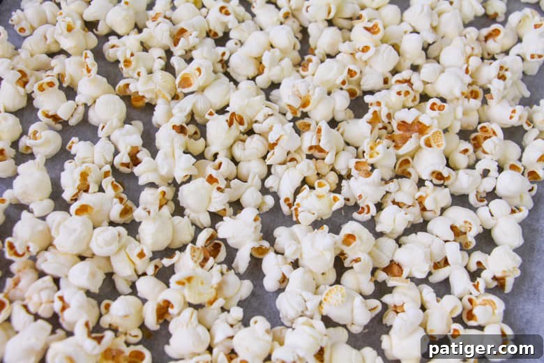 Popped popcorn spread on a lined baking sheet