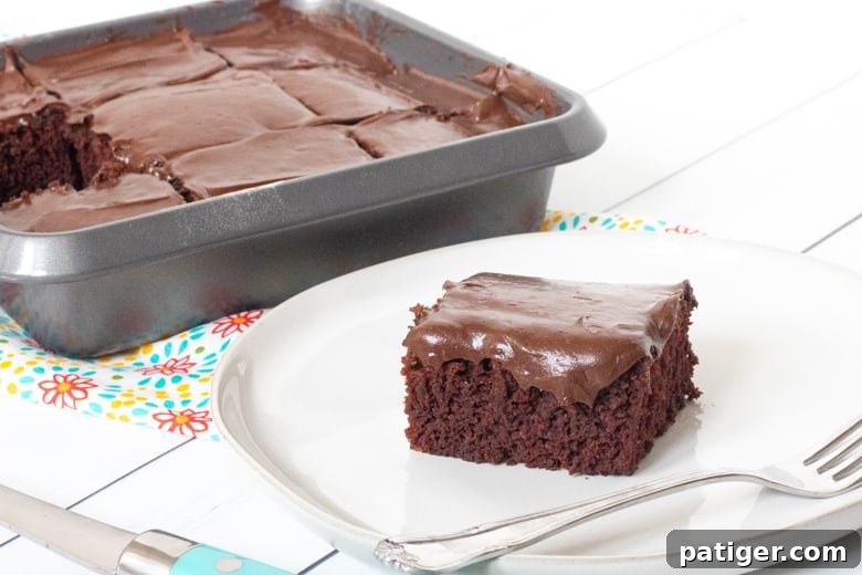 Crazy Wacky Cake in a 9 inch pan sliced into 9 servings. One serving is plated next to the pan.