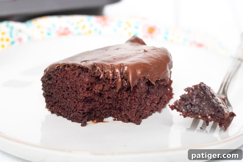 Moist crazy chocolate cake with chocolate frosting. A fork has taken a piece out of the cake and is resting on the plate.